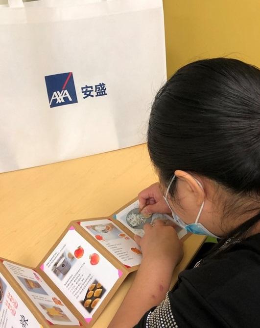 女青受眾用硬幣刮走於心靈加油繪本上的貼紙，便可看到企業義工的心意。