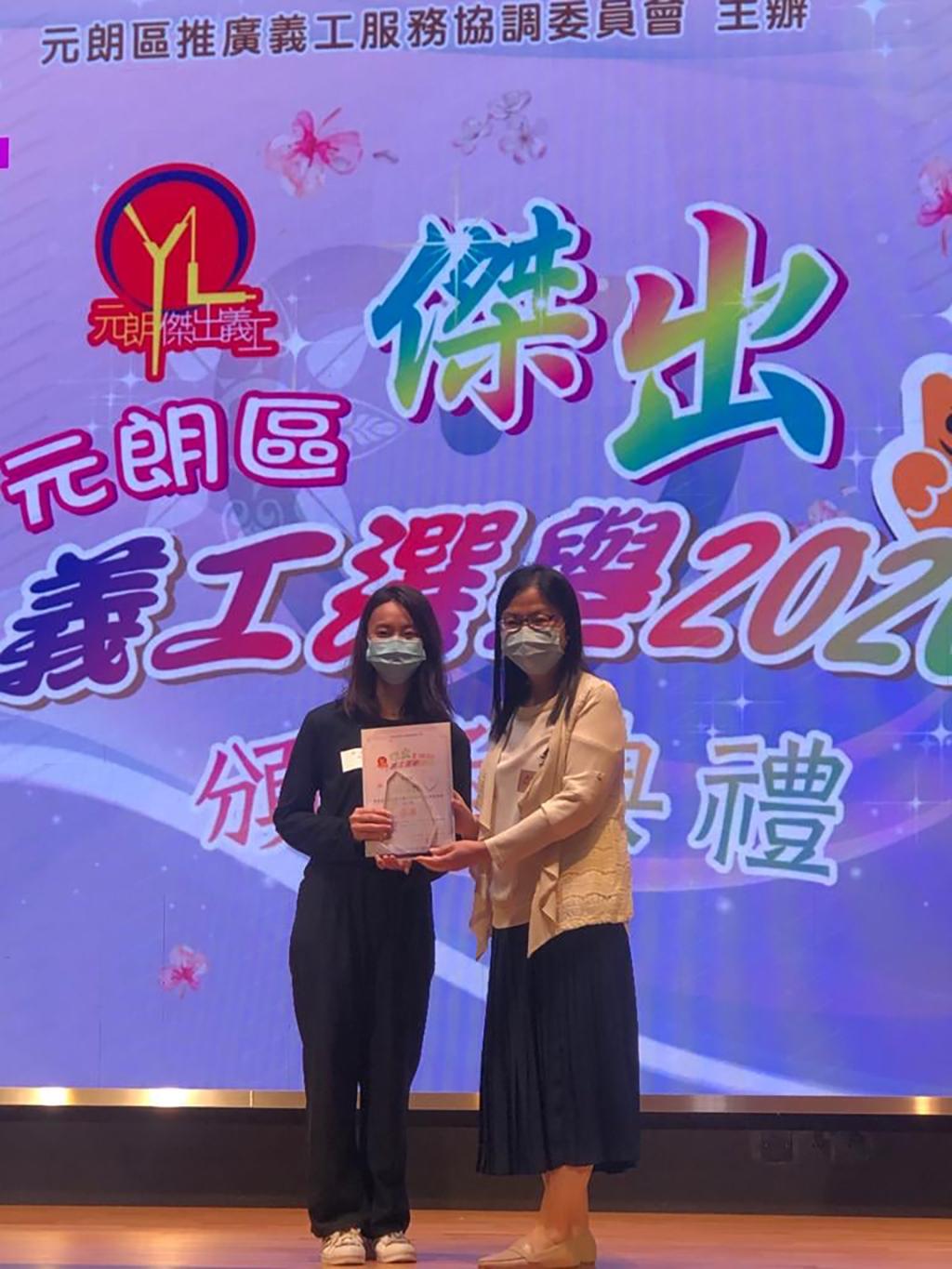 元朗區傑出義工選舉2020成人組季軍陳綺霞在頒獎台上接過獎狀。