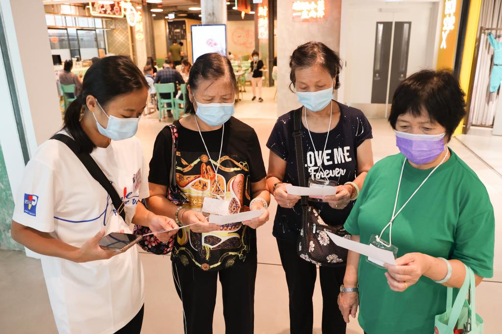 3名長者手持景點任務卡並在百佳義工陪同下在南豐紗廠內四處探索。