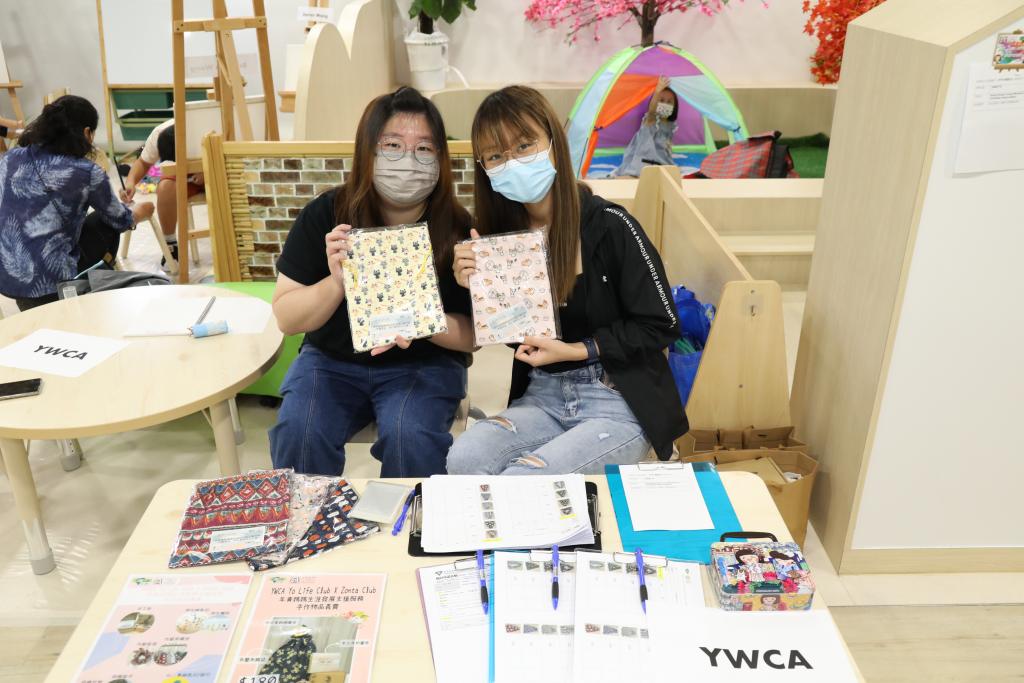 兩名年青媽媽手持親手製的作品於義賣攤位合照。