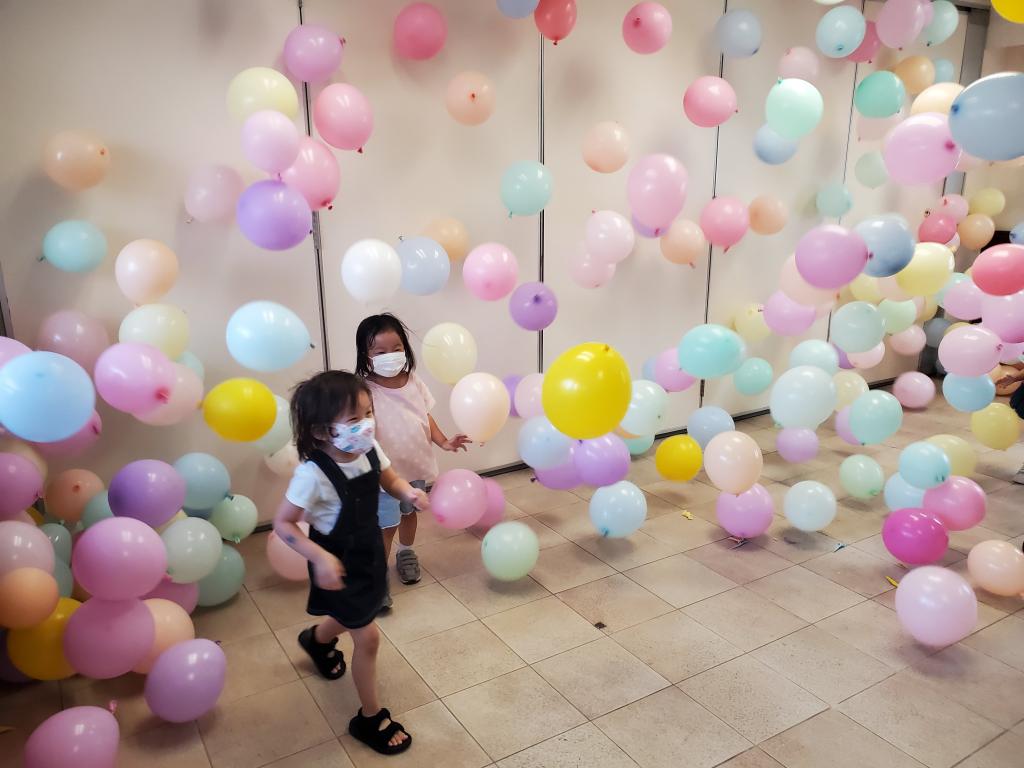 兩名小孩在充滿氣球的房間玩耍。