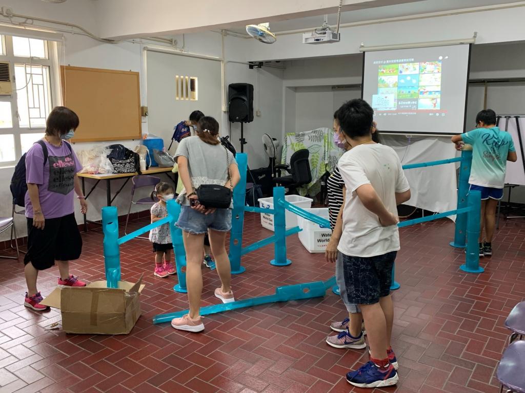 數名小童及其家長以藍色水管搭建模型。