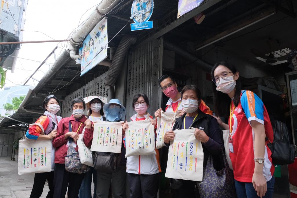 The participants took a photo with the shopping bags in front of the metal gate.