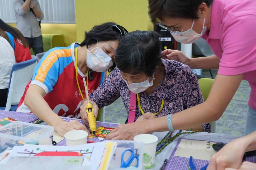 Instructor and volunteer assisted elderly to make the mini flower board.
