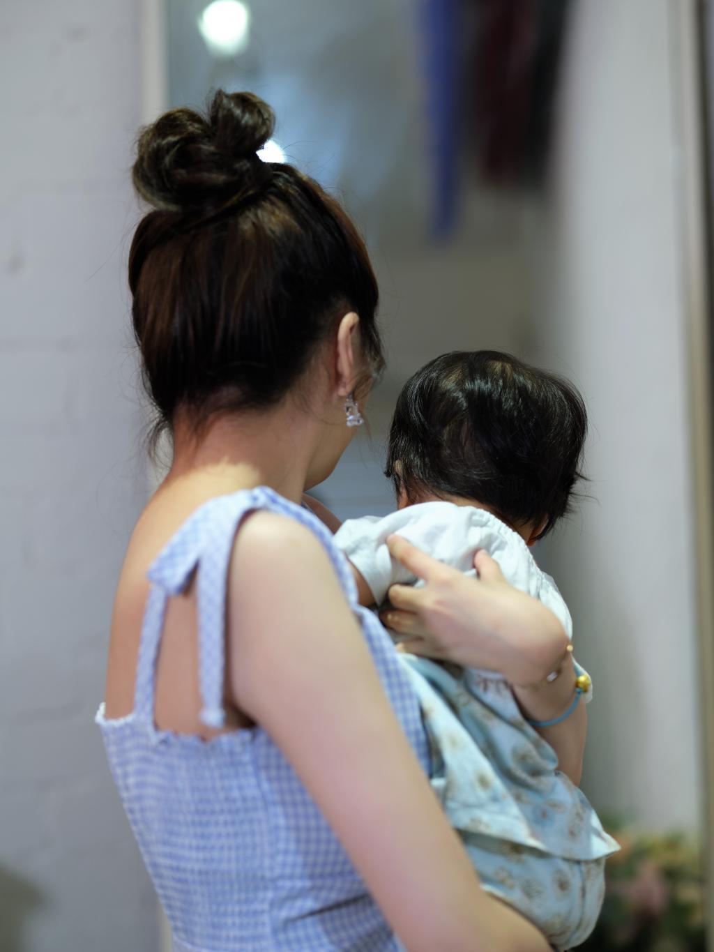 photo of a young mother holding a baby in her hands and with their back facing the camera