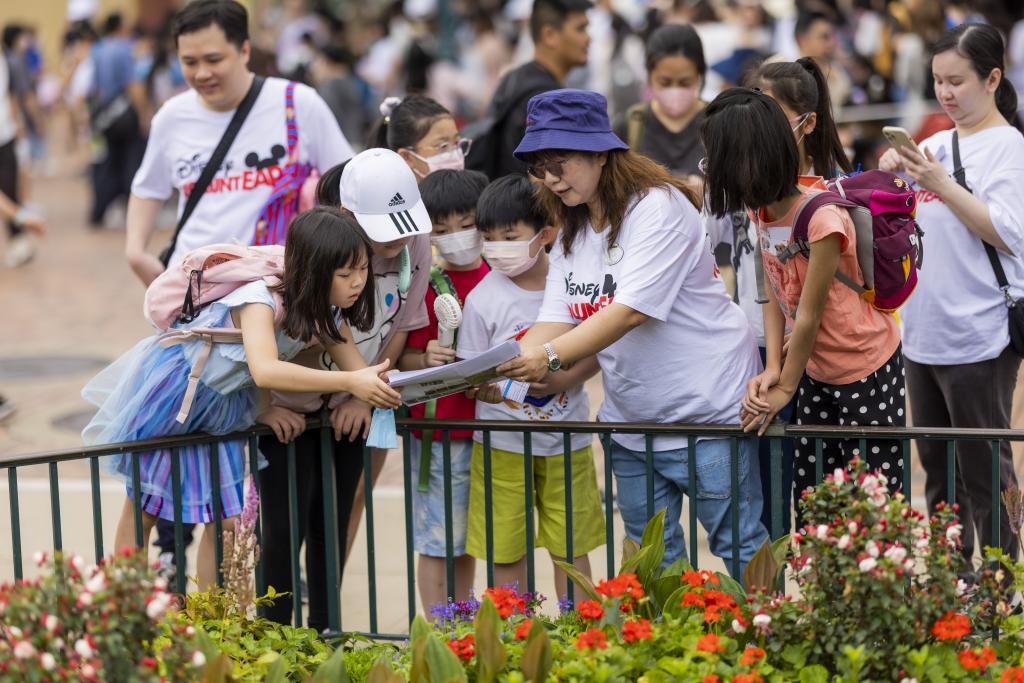 身穿迪士尼義工衣服的女士向一群孩子介紹花園中的植物