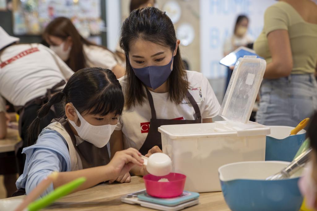 一名女義工與小孩一同量度材料。