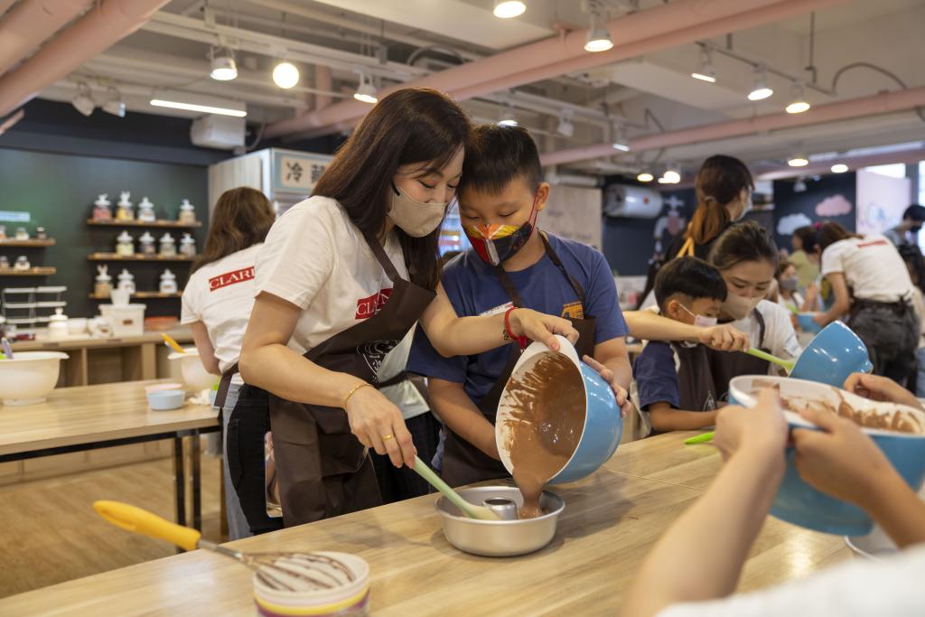 一名女義工與小孩一同 將材料倒入圓形模具內。