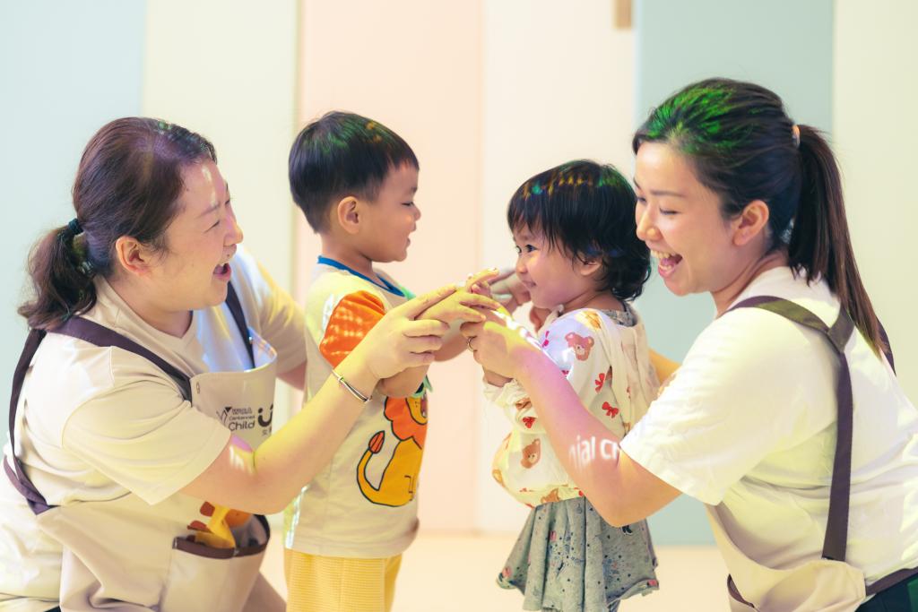 兩名嬰幼兒和教職員在玩耍