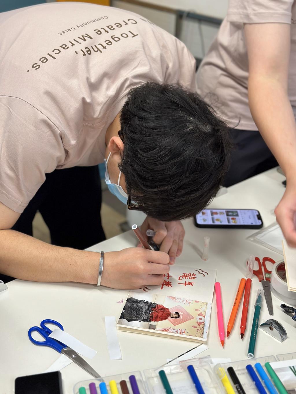 A volunteer was drawing a greeting card to elderly.