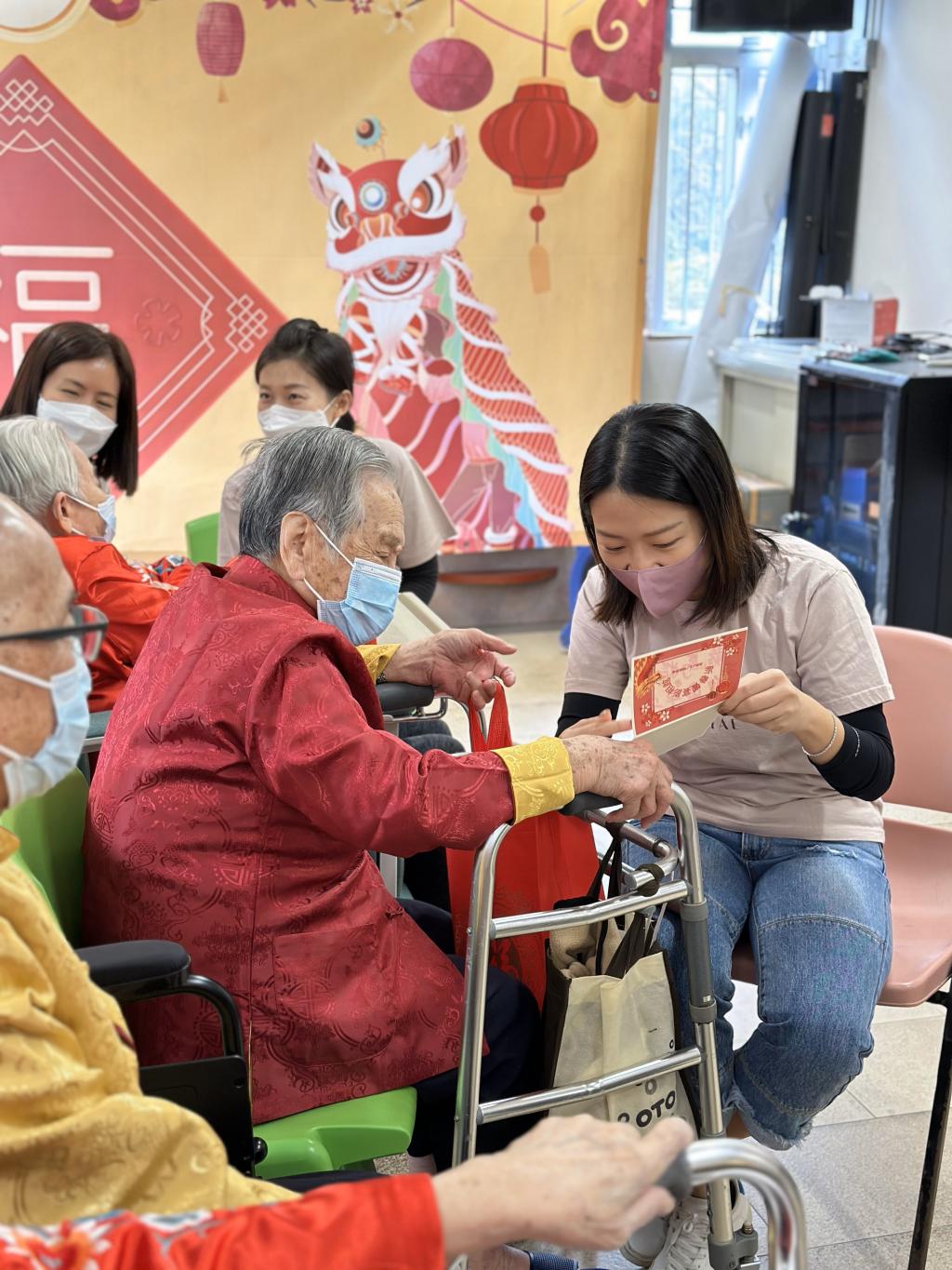 A lady volunteer was presenting the greeting card and photo to the senior lady
