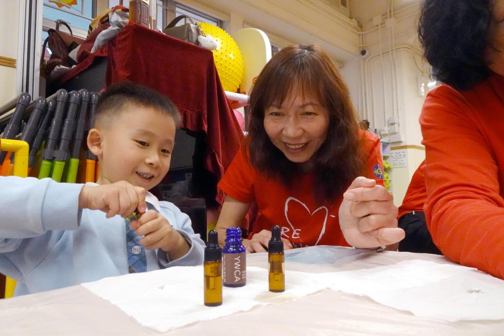 With the assistance of volunteers from The Hong Kong Jockey Club, young children mix their own special 'Mom's Scent' massage oil.