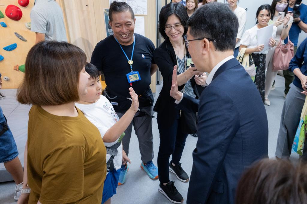 社會福利署署長杜永恒先生（右）鼓勵學童勇於攀上石牆，接受登頂挑戰。