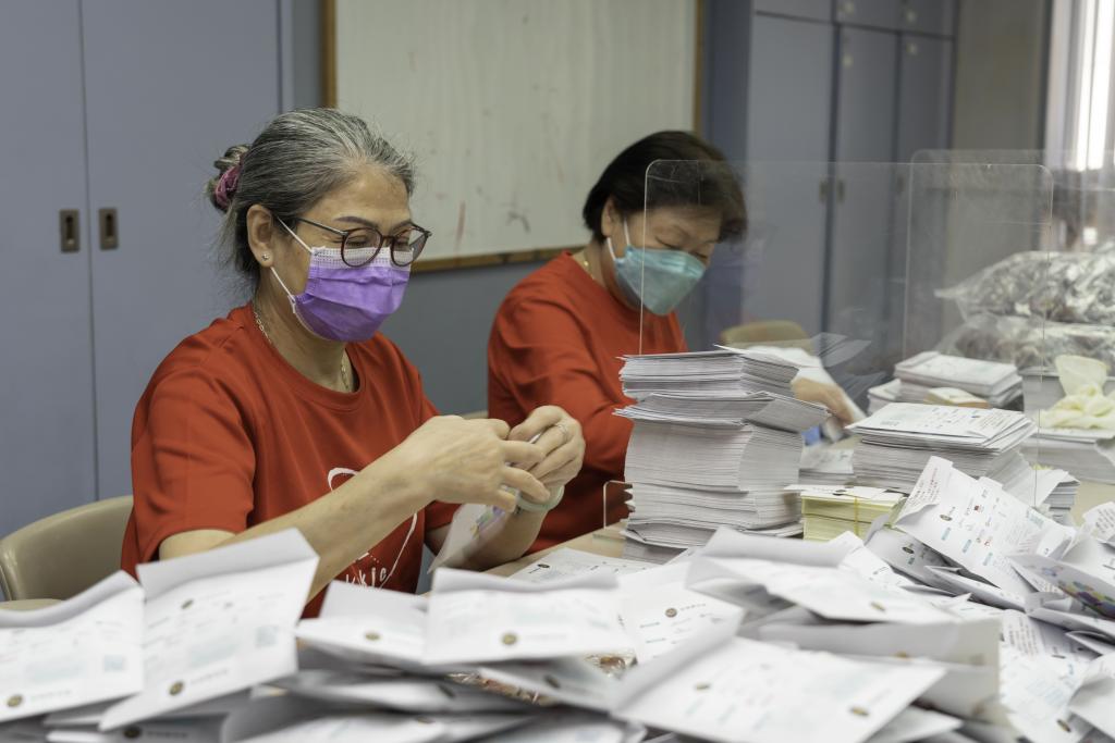 一位女士將紅棗及圓肉放入宣傳紙袋